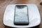 Broken Cellular Telephone. A Cellular Telephone with a cracked and broken Screen on a white plate on a table. Broken Cell Phone