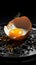 A broken chicken egg displayed on a somber black plate, raw vulnerability