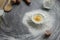 Broken chicken egg in a pile of flour, olive oil, milk, kitchen tool, gray table