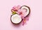 Broken coconut with tropic flowers on pink background
