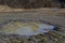 Broken country dirt road in spring mountains with lots of muddy puddles after the rain