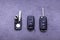 Broken or damaged remote key fob and new vehicle key on gray background. Broken or damaged remote key fob of any vehicle car