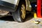 Broken down car in a mechanic shop, near a jack lift, showing the bottom wheel and tire of the car parked in the garage repair