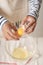 Broken egg in hands with separated yolk closeup