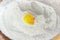Broken egg in sifted flour in bowl closeup