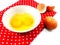 Broken eggshells with egg yolks in ceramic bowl with red polka dot fabric