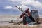 Broken fishing boat wreckage on a sandy beach under bad weather