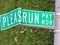 Broken funny road sign bent to look like Please Run or â€œPLEASRUNâ€ lying on the grass