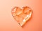 A broken glass heart on a pink background, on peach fuzz background.