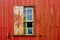 Broken glass and wood window from abandoned house facade with old peeling red wooden wall and grungy surface texture