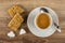 Broken granola bar with chocolate, pieces of sugar, cup with coffee and spoon on saucer on table. Top view