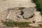 A broken gray reinforced concrete manhole cover sits on an asphalt road. Danger to cars and pedestrians. Poor city block