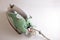 Broken green electric iron with access to the wires and the contact group in the back. Home appliance repair concept. Copy space.