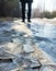 Broken ice on the track in the park against the background of men legs in dark jeans