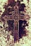 Broken iron crucifix on old mossy tombstone