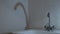 Broken old metal faucet on white kitchen sink and shadow on wall.