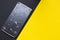 A broken phone on yellow and black background. Crushed device with broken screen representing an accident. Textured screen with