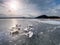 Broken pieces of thick ice over frozen lake shine in sun.