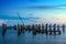 Broken pier and mast of broken ship in water after sunset