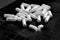 Broken pill and spilled medical dust. Many white pills on black background. White tablets, medication