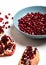 Broken pomegranate and pomegranate seeds in blue plate. Garnet seeds. White background. Closeup.