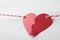 Broken red paper heart and rope on white wooden table, closeup. Cheating concept