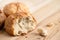 Broken round rustic white bread roll next to two round bread rolls on light wood