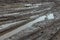 A broken rural country road after the rain. Puddles after rain on a dirt road. Clay, soil and puddles at cloudy day