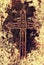 Broken and rusty iron rustic crucifix on old mossy tombstone. Abandoned symbol of religion.