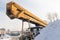 Broken rusty truck crane with yellow boom covered with snow on a cold winter day