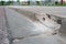 Broken sidewalk curb with exposed rebar and jagged edges that could cause a tripping hazard