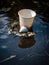A broken styrofoam cup floating in a polluted lake.. AI generation