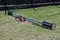 Broken vintage retro old blue metal playground seesaw with wooden seats surrounded with grass and metal fence in background