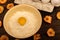 A broken white chicken egg in a bowl with wheat flour, dried apple chips and several whole eggs in a tray made of white cardboard