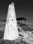 Broken white conical concrete structure next to a shelter on the coastal cliffs surrounded by spring flowers in paphos cyprus