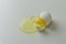 Broken white egg with egg shel and yolk on gray background