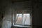 Broken window with curtains fluttering in wind in old abandoned building interior