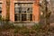 Broken window in red brick wall of deserted 1970s` workshop