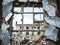 A broken window in the wall of a dilapidated and abandoned house.