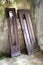 Broken wooden house doors leaned to moldy wall in abandoned house