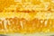Broken yellow honeycomb with honey on plate