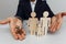 Broker holds a house keys. Wooden figures of a family ahead. Mortgage concept