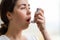 Bronchial asthma. Close-up portrait of a young woman holding an inhaler to her mouth. Blurry background