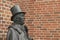 Bronse statue of th danish author H C Andersen in profile against a red brickwall