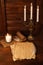 Bronze candlestick with three burning candles on a wooden brown table. Old parchment.