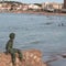 Bronze child sculpture starring at the beach