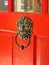 Bronze doorknocker on red wooden door