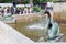 A bronze fountain monument with bird in a city park in Stockholm Sweden. People defocused in the background