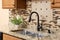 A bronze kitchen faucet detail with wood cabinets and tiled backsplash.