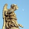 Bronze statue of an Angel, in Rome, with a pale moon in the sky